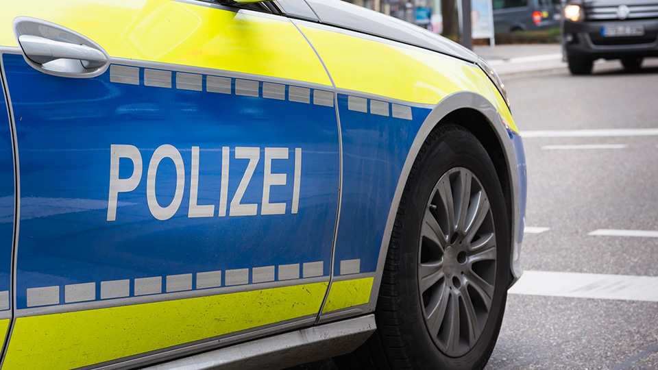 Polizeiauto von der Seite: Schriftzug POLIZEI im Vordergrund.