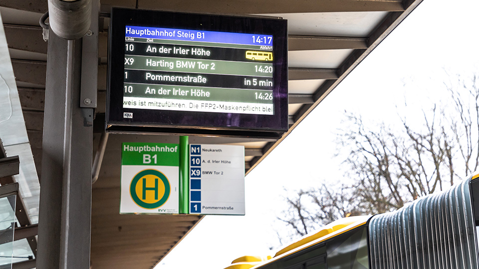 Elektronische Anzeigetafeln für den Busverkehr. Rechts ist der obere Ausschnitt eines Stadtbusses zu sehen.