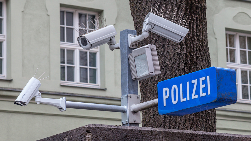 Polizei Schild in Blau-Weiß und Überwachungskameras.