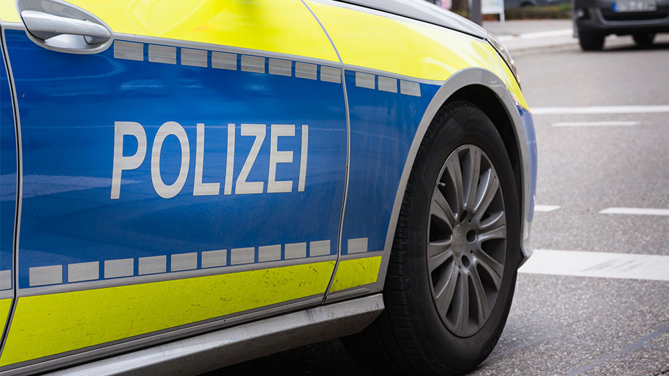 Streifenwagen der Polizei von der Seite, der Schriftzug "POLIZEI" ist dabei im Vordergrund.