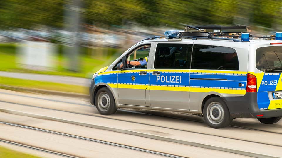 Streifenwagen der Polizei während der Fahrt von der Seite. Der Schriftzug POLIZEI ist dabei sichtbar.