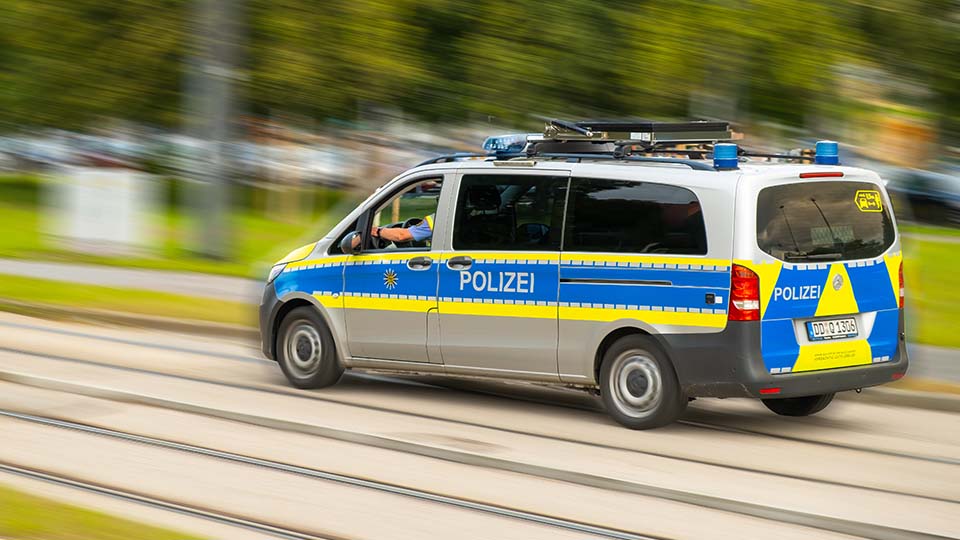 Streifenwagen der Polizei während der Fahrt von der Seite. Der Schriftzug POLIZEI ist dabei sichtbar.