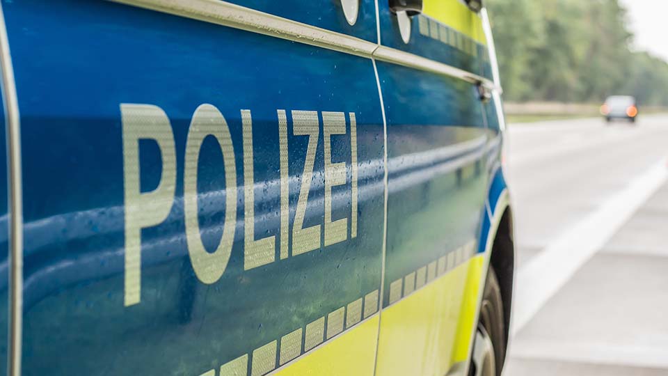 Streifenwagen der Polizei, der gerade am Fahrbahnrand steht, von der Seite: Schriftzug POLIZEI im Vordergrund.