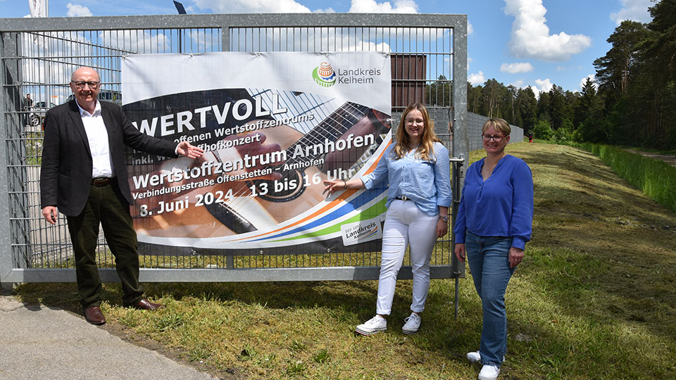 Landrat Martin Neumeyer, Abfallberaterin Katharina Spreider und Michaela Kilic, die Sachgebietsleiterin der Kommunalen Abfallwirtschaft (v. l.) mit dem Banner, das auf den Tag des offenen Wertstoffzentrums Arnhofen hinweist. 
