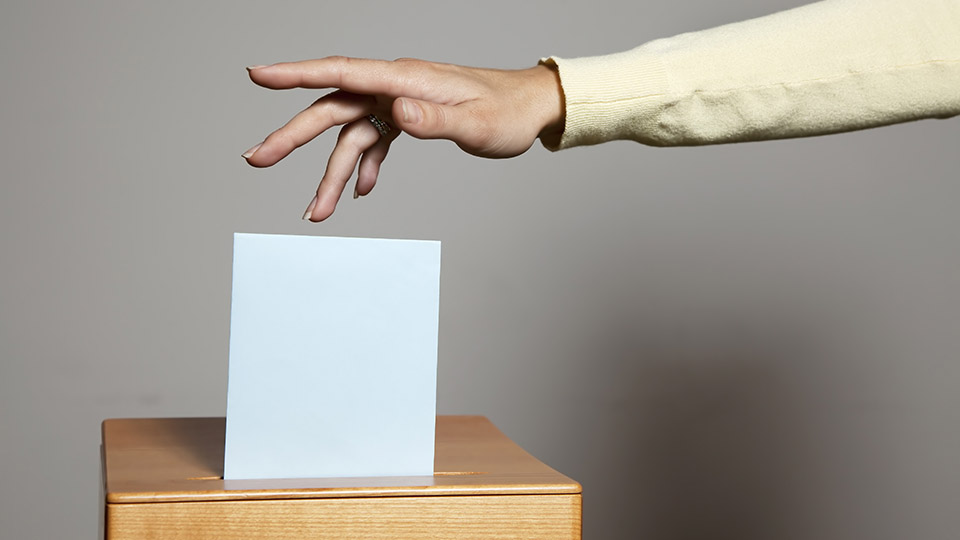 Europawahl: Frau wirft Wahlzettel in Urne.
