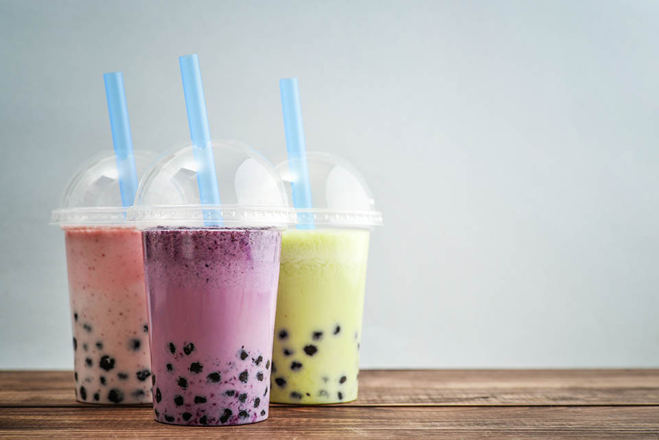 Various Bubble Tea in a plastic cups with drink straws on blue background. Take away drinks concept.