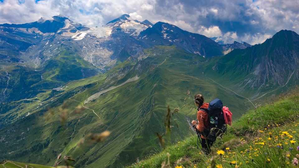 Frau steht auf den Bergen und sieht hinab ins Tal